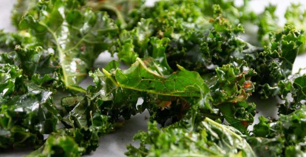 seasoned kale spread on a baking sheet ready for roasting